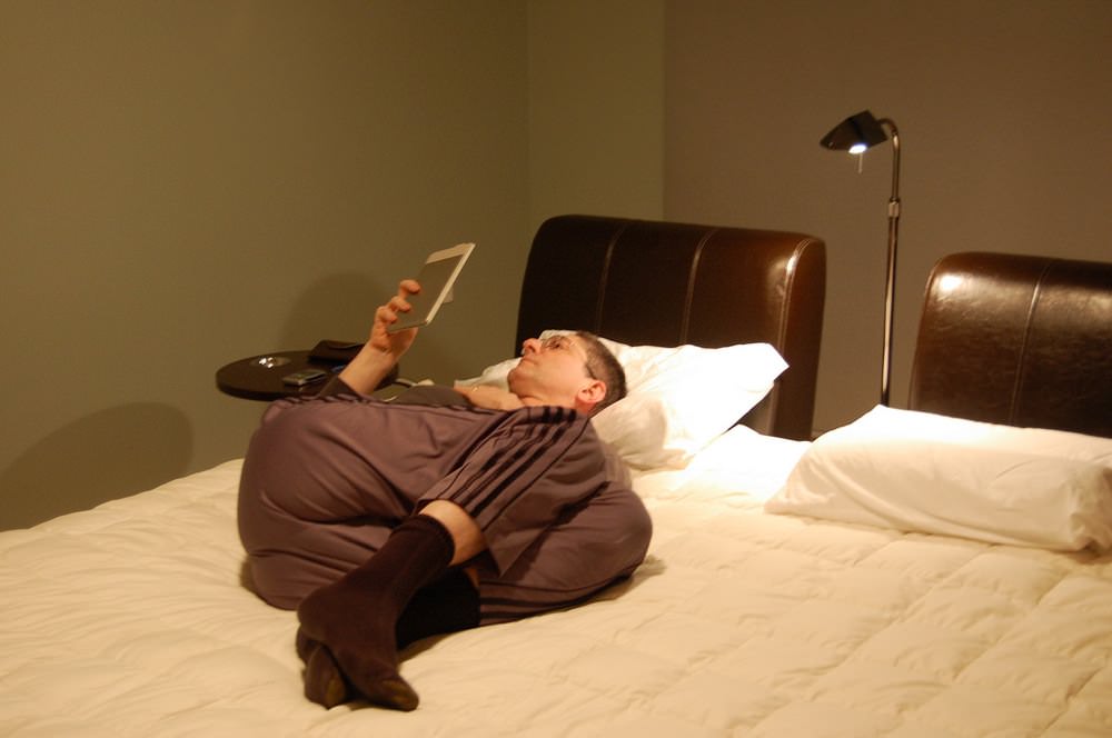 He's reading kindle on the bed