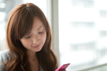 携帯電話でメールを打つ美人女性